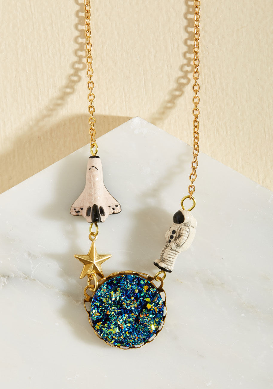  - Be warned - wearing this gold necklace by Eclectic Eccentricity will inspire a quick trip to the planetarium! The observatory displays galaxies which resemble your accessory&rsquo;s druzy-inspired blue cabochon, while its astronaut and shuttle charms enco