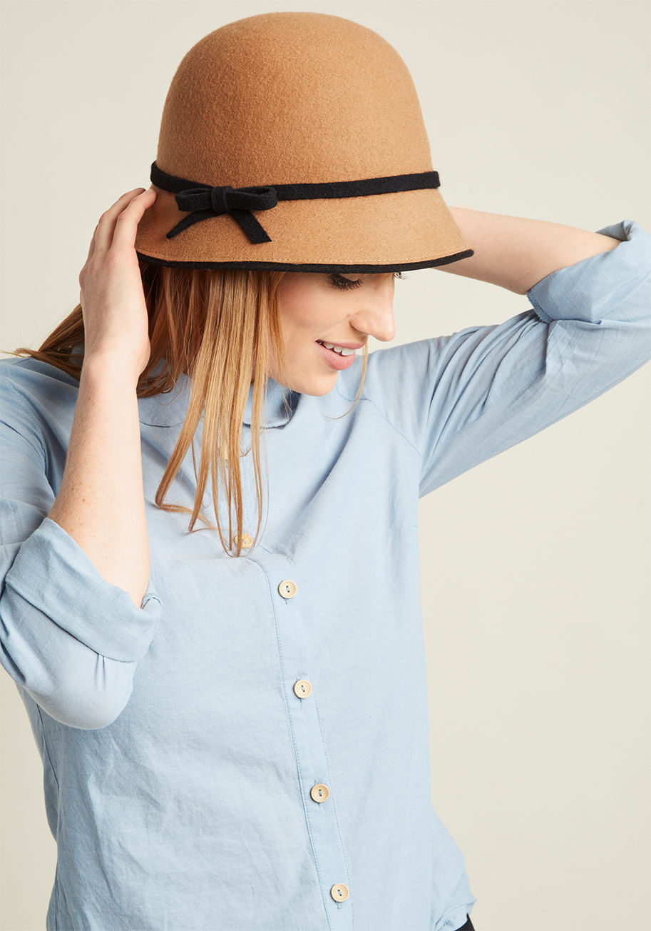  - Come one, come all, come and admire this tan cloche hat! A vintage-inspired style to swoon for, this charming topper will have everyone approaching you with enthusiastic compliments for its black trimmings, adorable bow, and nostalgic vibe.