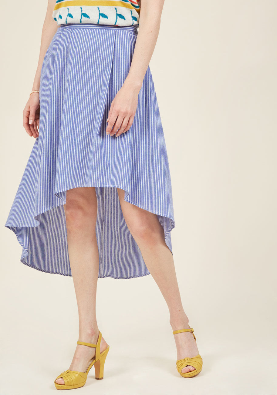  - The magic of this chambray skirt can transform the even most casual gait into a show-stopping strut! While the pleats, high waistline, and white pinstripes of this blue beauty are all appreciated design elements, it's the wind-catching high-low hemline th