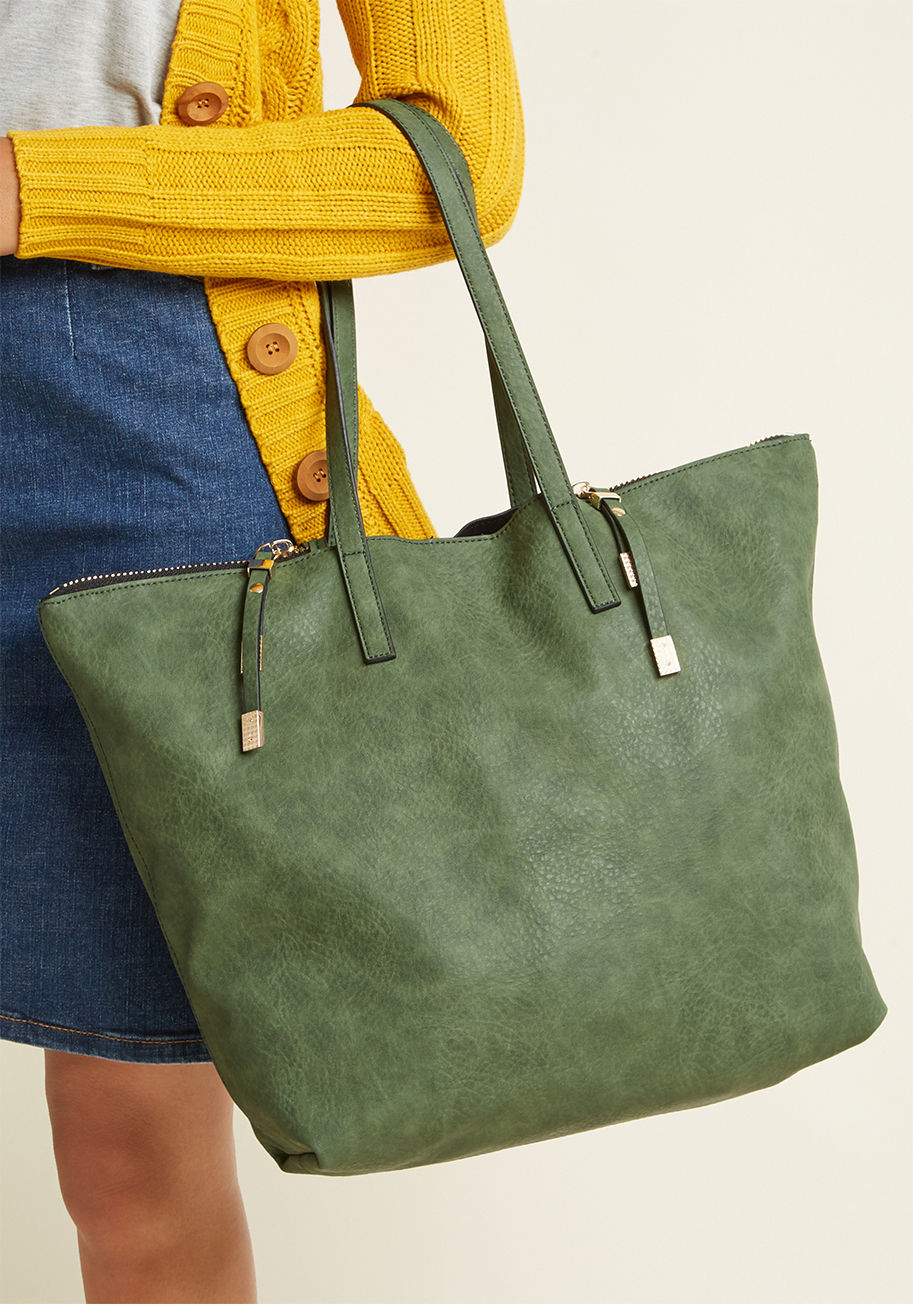 10874BML - What's holding you back from going all the way with this moss green carryall? Its roomy, faux-leather compartment is secured by a magnetic snap and golden side zippers - fastened by high-fashion pulls - and its handles are the perfect over-the-shoulder le