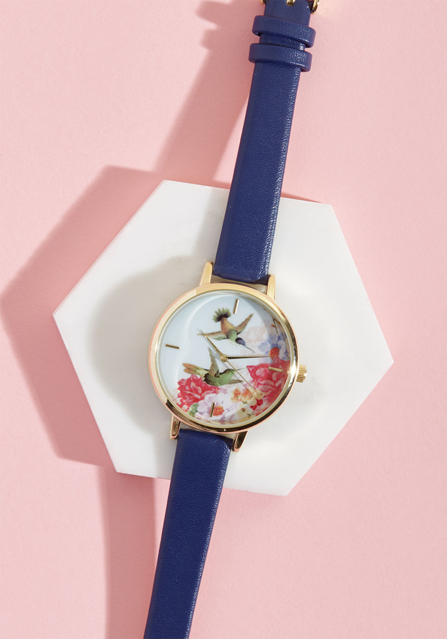 15257 - The elegance of this printed watch has no expiry! Upon fastening the navy blue, faux-leather band of this chic timepiece around your wrist, and taking a moment to witness the gold-framed scene of hummingbirds frolicking amongst the flowers atop its round 