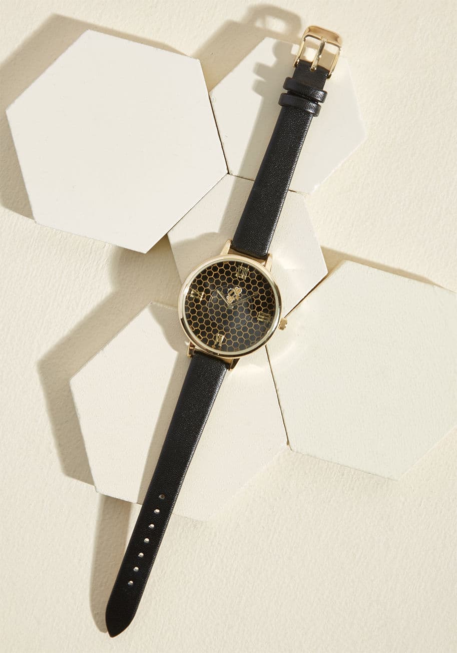 15261 - Pondering the possibility of adding a timekeeper to your jewelry box? Then, consider this black watch! With faux-leather straps and a shiny gold rim, this clock keeps it classy. But, don't forget the dapper roman numerals, hexagonal honeycombs, and circli