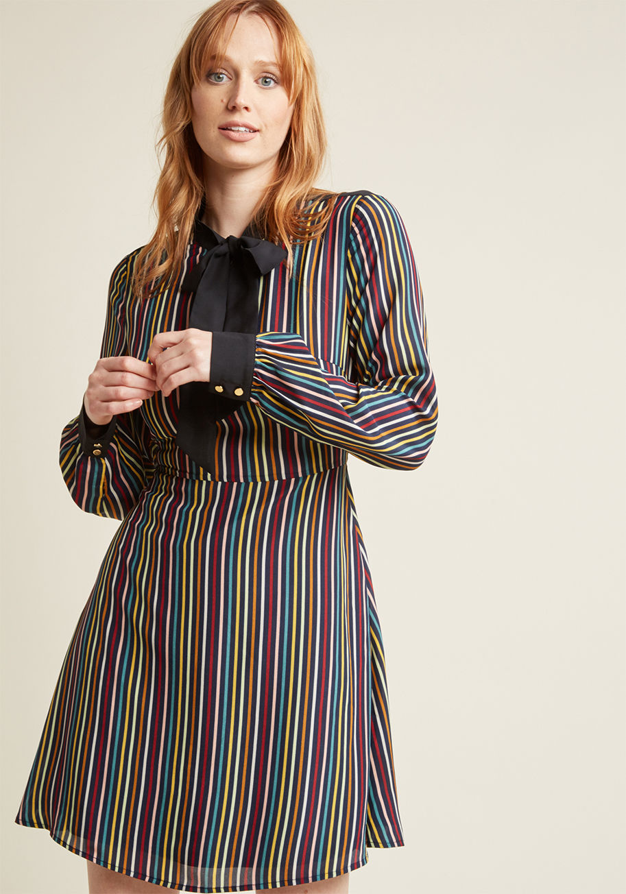 24505D - Forget looking to the calendar for the perfect moment to show off this navy striped dress! From Sunday to Saturday, this multi-hued beauty promises a most impactful look, all thanks to its black neckline tie and sheer back panel, cuffed sleeves, and A-lin