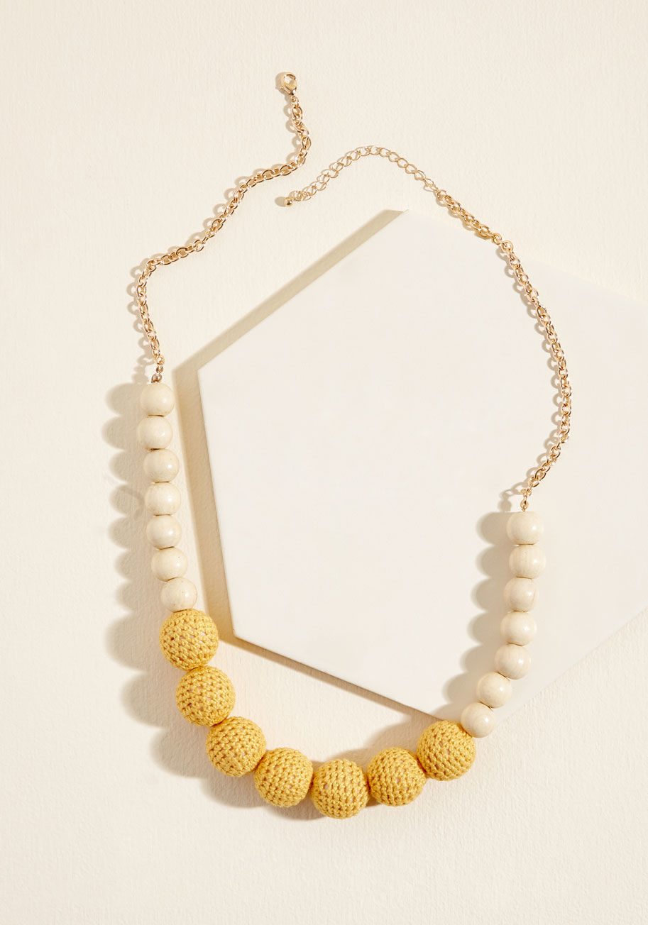 456450N-101 - When something tells you it's time to rock this statement necklace, you listen to that notion! Adjusted behind your neck with golden cable chains, this eye-catching piece showcases blond wood beads and mustard crocheting-covered baubles that bring an elem