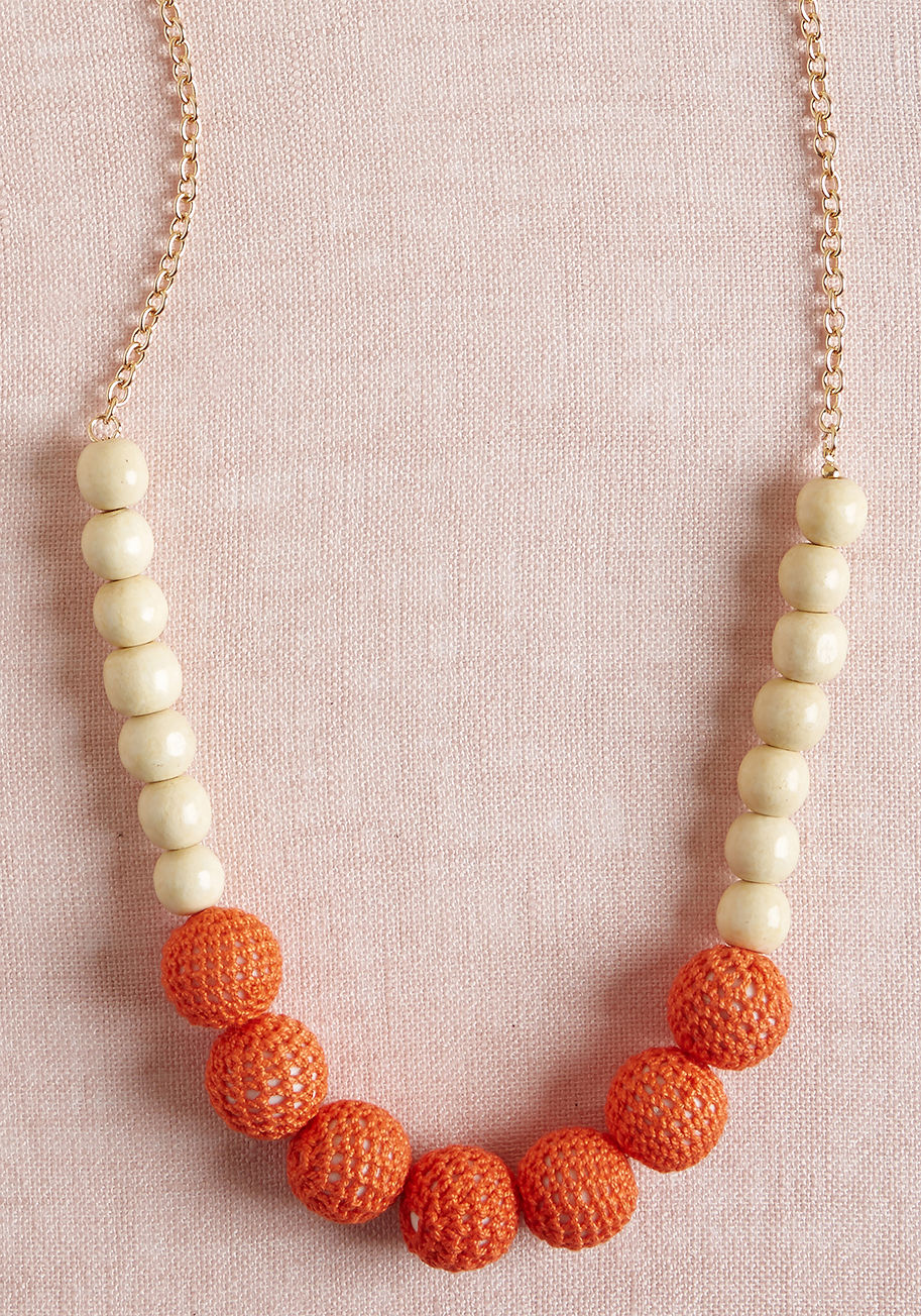 456450N-103 - When something tells you it's time to rock this statement necklace, you listen to that notion! Adjusted behind your neck with golden cable chains, this eye-catching piece showcases blond wood beads and coral crocheting-covered baubles that bring an elemen