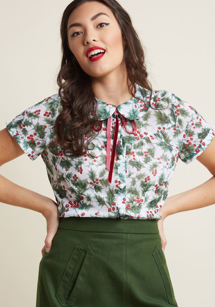 6605 - Exclamations for the festive nature of this white button-up are inevitable! A vintage-inspired find from Hell Bunny, this chiffon blouse - with its velvet neckline tie below a Peter Pan collar, sleek seams, and green-and-red holly print - declares itself 