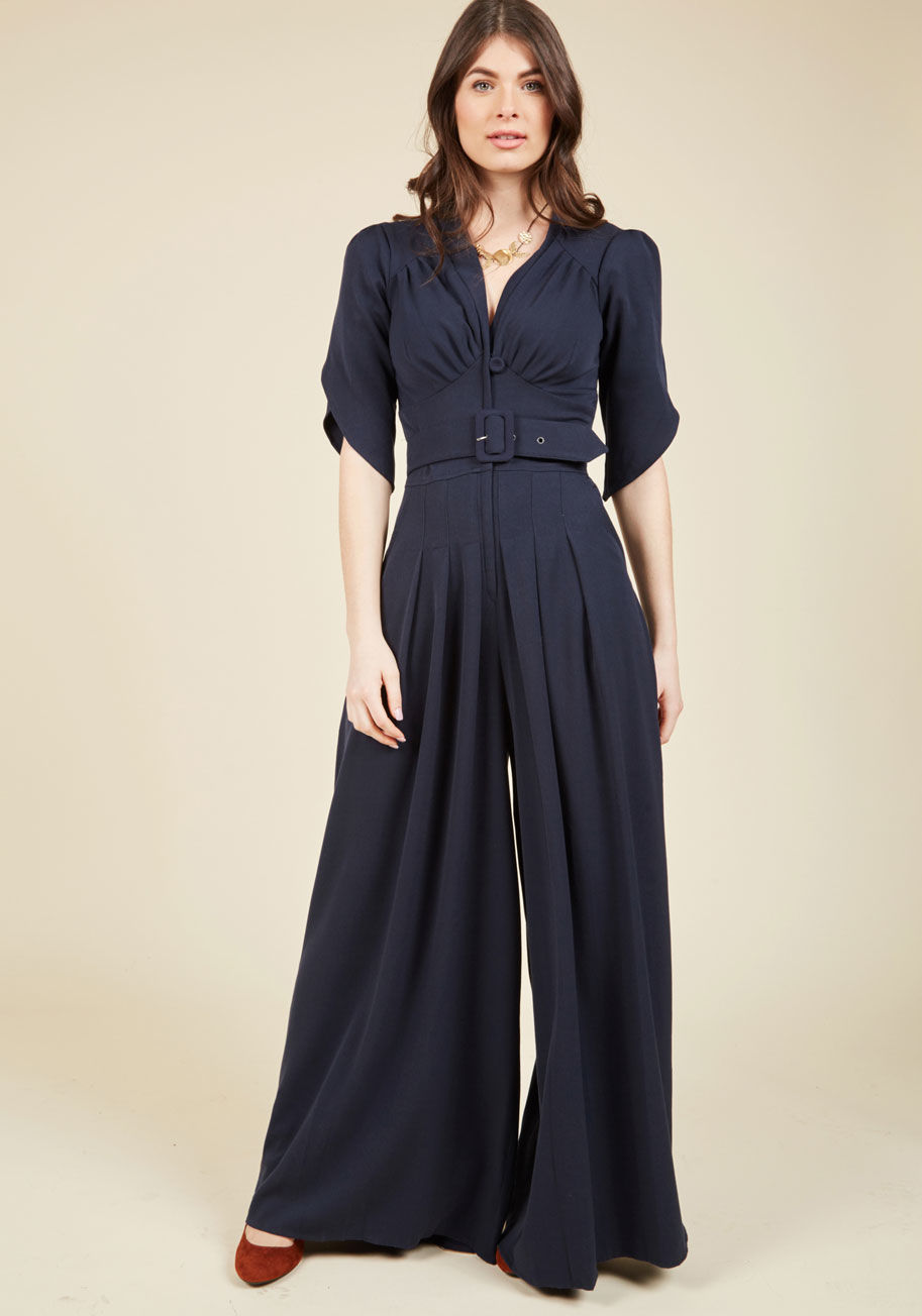 755PL - In this golden era of inspiration, you feel encouraged to sport this bold navy jumpsuit. Inspirited by its gathered bust, tulip-style half sleeves, and broad waistband boasting a self belt, you step out like a starlet, swishing the pleated, skirt-like leg