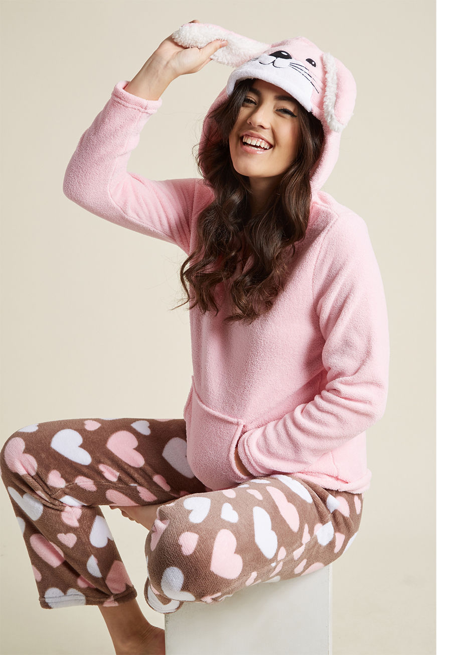 82131 - It&rsquo;ll be downright impossible not to giggle with glee when you don these pink PJs! From the top's whiskered face to the the grey, heart-printed pants, these super-soft fleece pajamas are as cozy as they are kawaii. And, with a floppy-eared hood to b