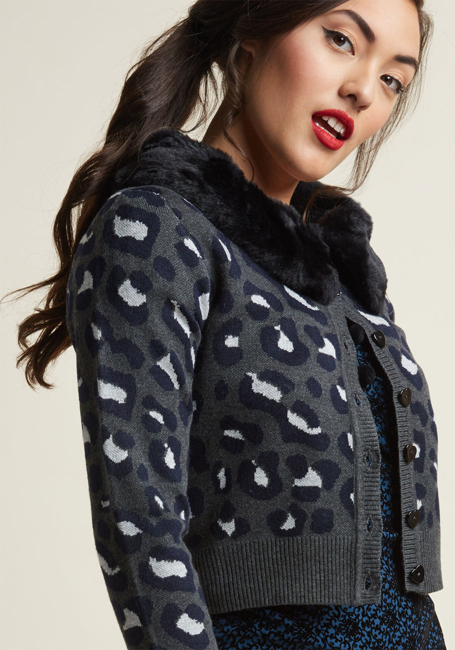 AW170101B - Take your love of retro style to bold heights by tossing this grey cardigan into the mix! On their own, this Collectif sweater's navy and white leopard spots, black heart-shaped buttons, and cropped cut are alluring, but it's the addition of a removable f