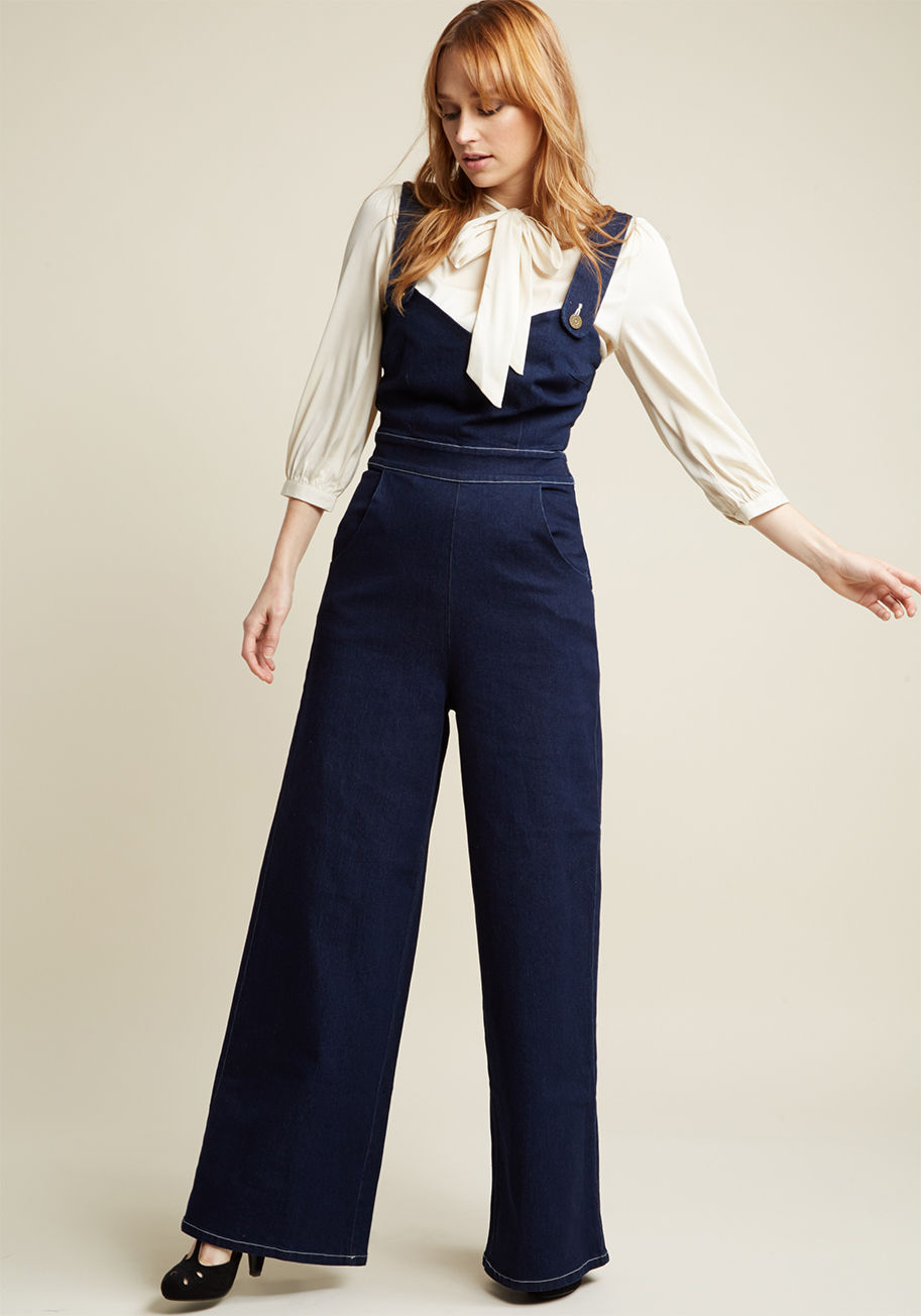 AW172001A - Making a lasting impression is as simple as buttoning into these dark wash overalls by Collectif! Irresistibly retro, this wide-leg pair is one that's easy to commit to memory thanks to its sweetheart neckline, high waistline, heart-stitched pockets, and 