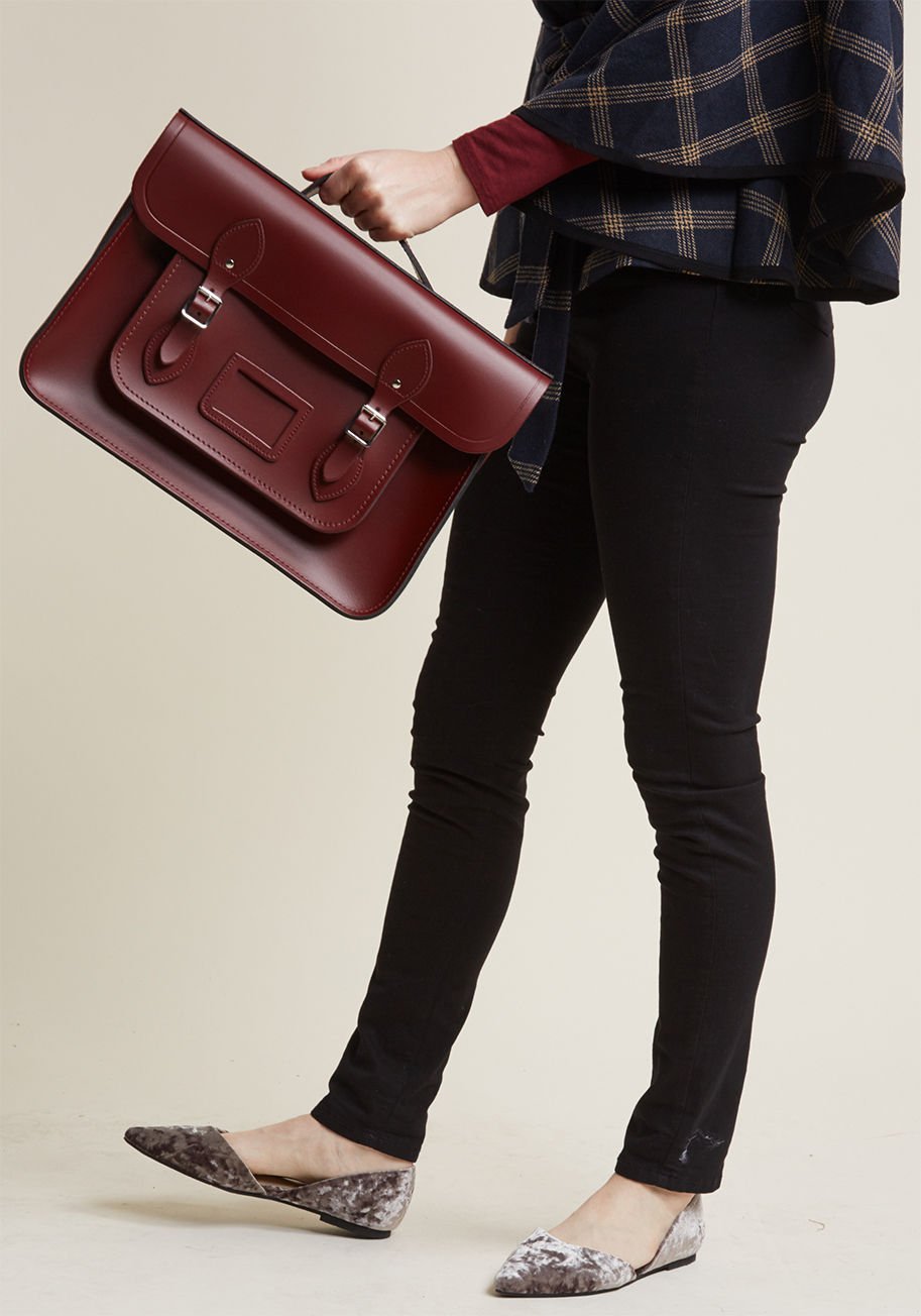 BAT151005BNH10101 - This burgundy bag, undeniably designed by The Cambridge Satchel Company, is absolutely saturated with classic style! A sturdy-yet-smooth, genuine leather composition hosts the handy magnetic buckles, luggage tag frame, dimensional front pocket, and essent