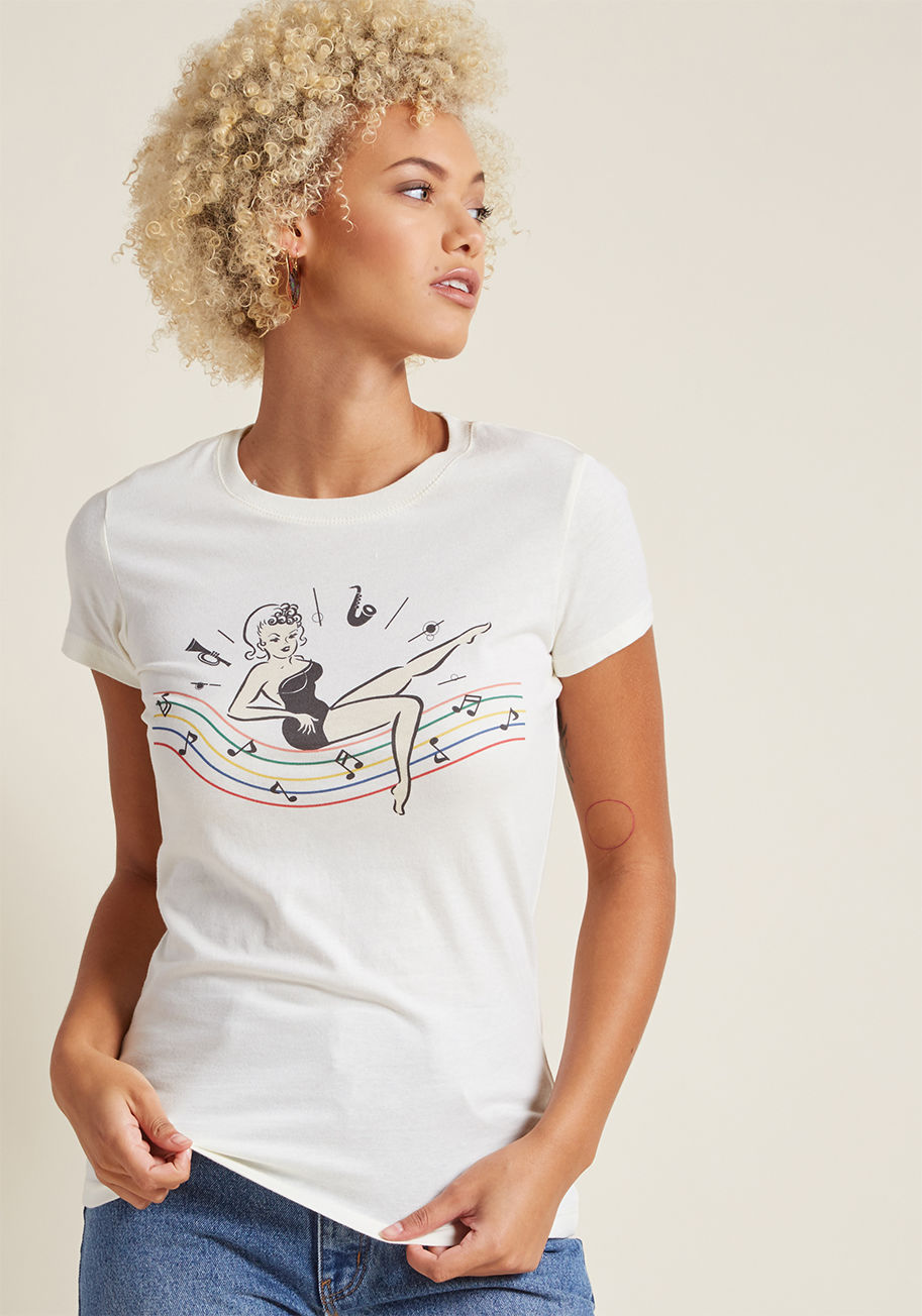 BETTY BOP - Flaunt your love of all things vintage with this ivory tee! Showcasing a sweet graphic of a pinup gal showing off on a rainbow of jazzy instruments and notes, this 100% cotton and USA-made tee is the perfect way to let the world witness your adoration for