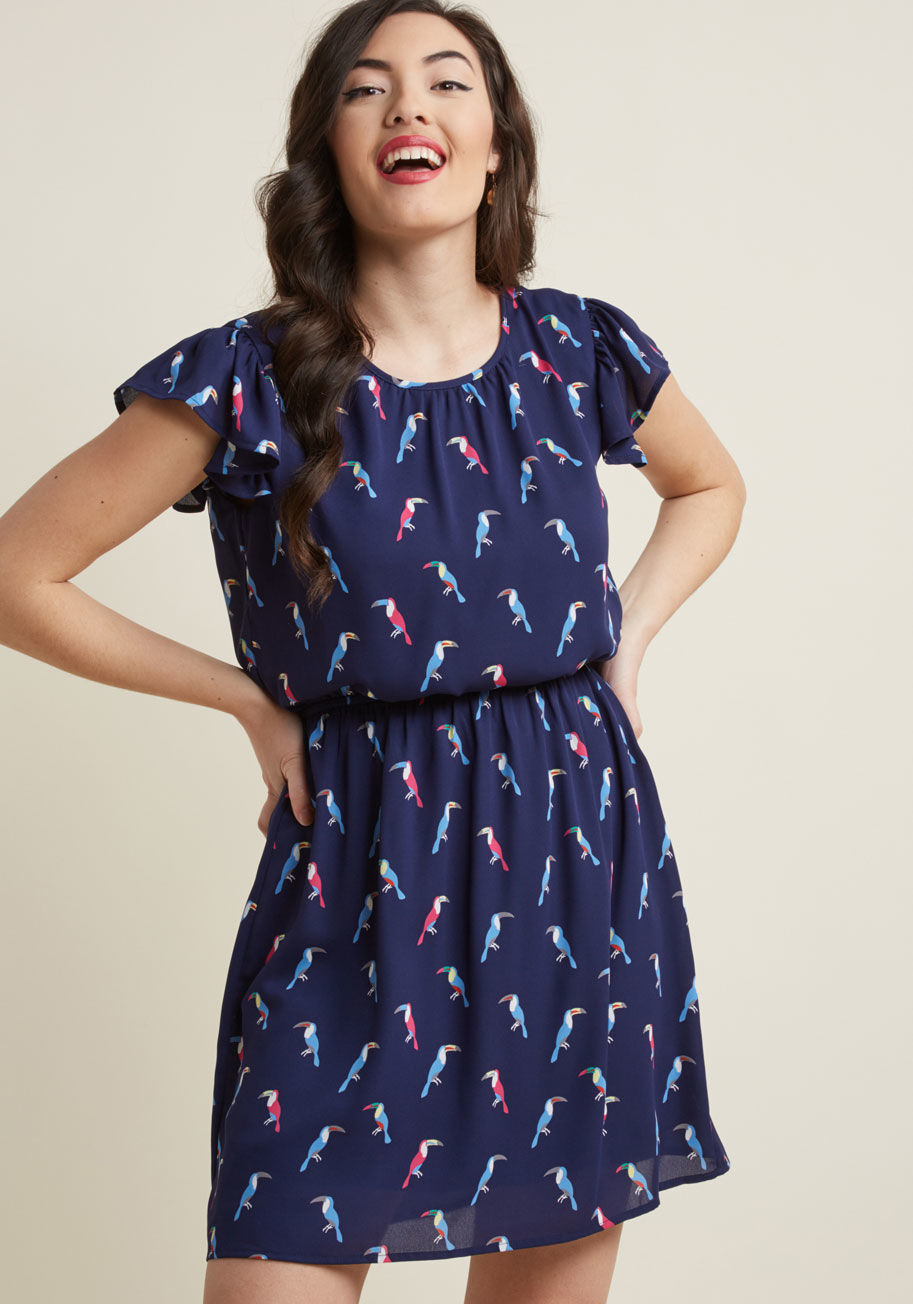 D22383-01 - Expressing your delight will be automatic as soon as you slip into this printed dress! A bevy of multicolored toucans hang out atop this navy blue frock, adding a touch of whimsy to its fluttery short sleeves and adorably cinched waist.