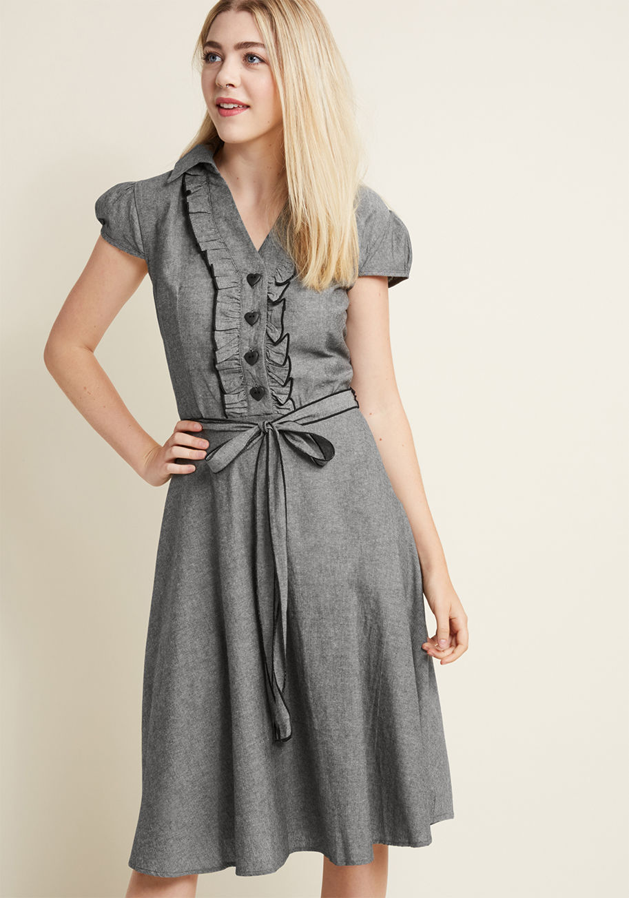 D3051 - This delightful grey shirtdress grew up dreaming about one day becoming a fashion icon. Today, it's on its way with dapper ruffles, heart-shaped buttons and precise black trim to round out its repertoire. Check out this dashing design