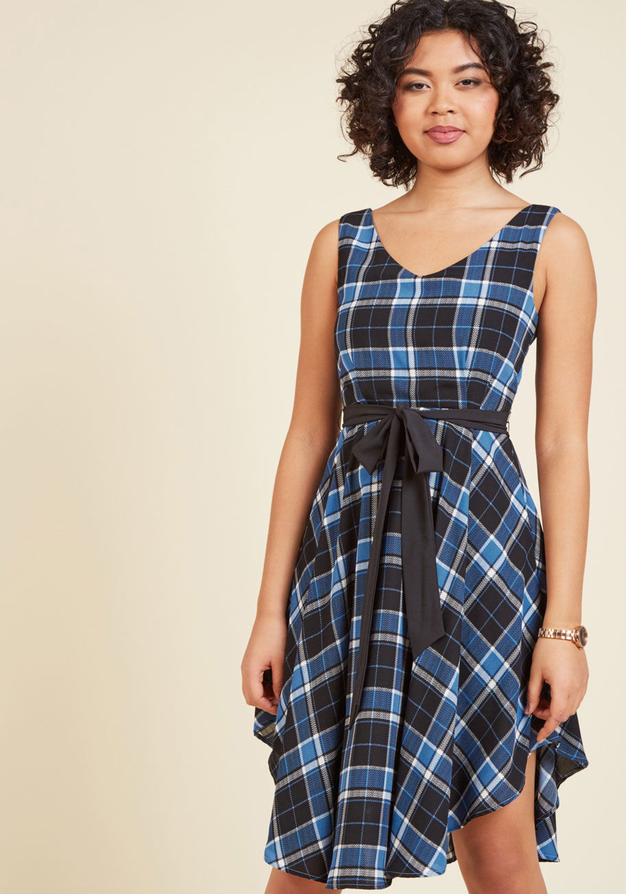 D8998 - The arrival of this plaid dress into your life puts an end to your ponderings over the perfect frock. Elegantly flowy and endlessly flattering, this black, white, and blue style spotlights soft pleats at the bodice and a curved hemline that makes every st