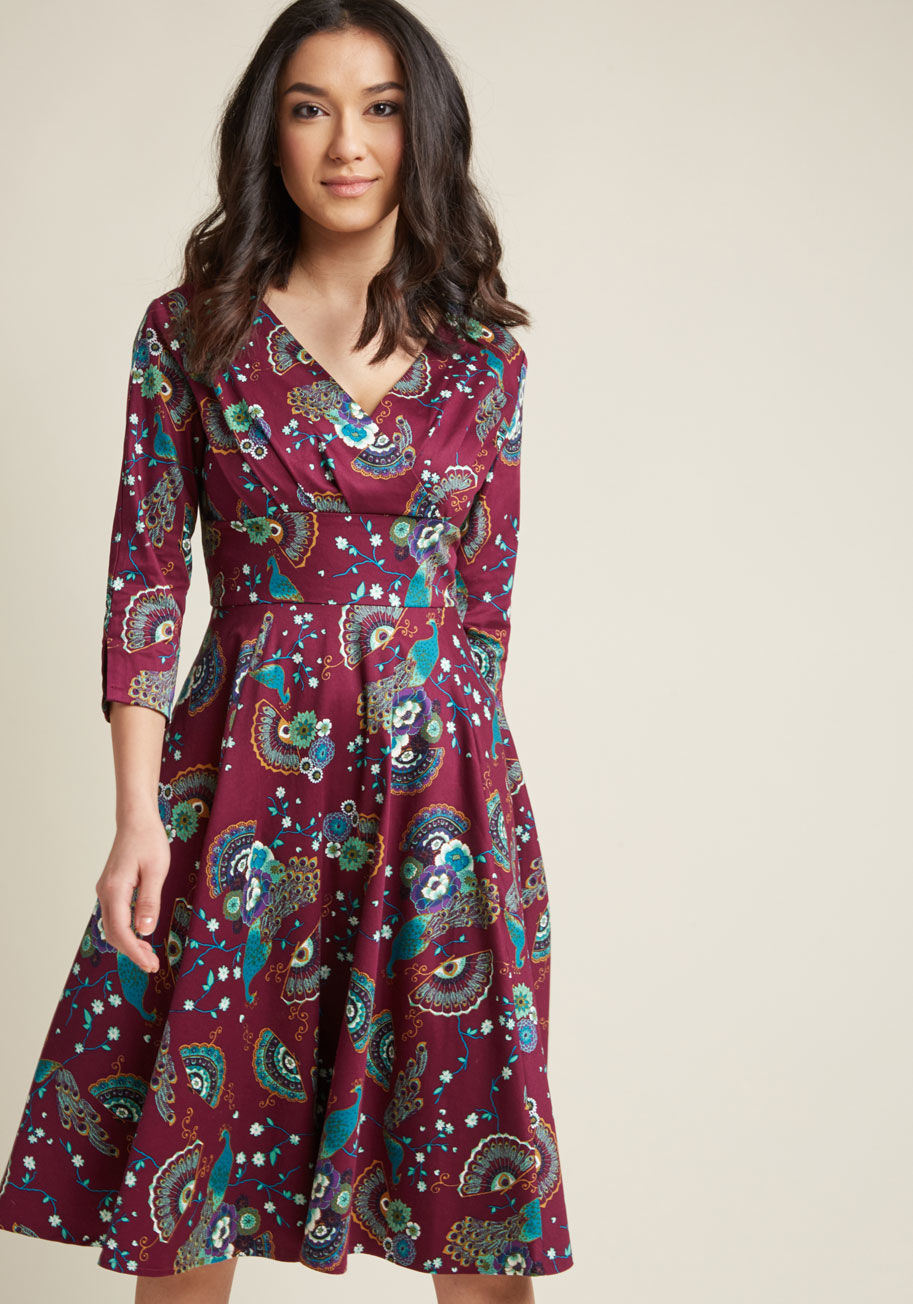 DR5362 - This 3/4 sleeve dress is one sure way to make a statement! Rocking a pleated surplice neckline, a broad waistband, vented sleeves, and an A-line silhouette, this stretch-cotton beauty is radiantly retro. Plus, the teal, purple, and gold fans, florals, and