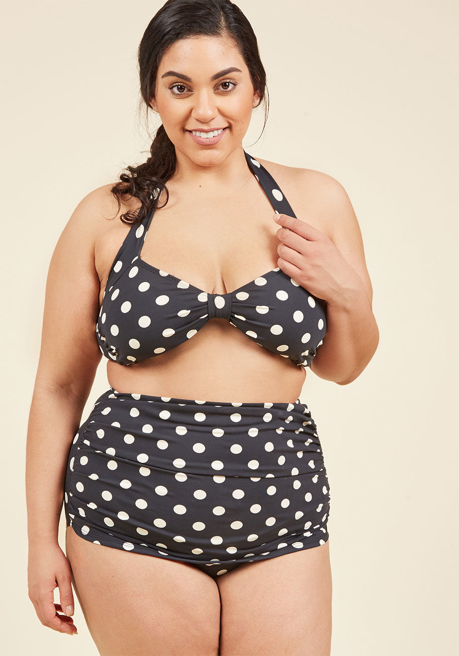 E09006 - Inspired by our favorite beach party film, this two-piece swimsuit is flattering on every body type. By the iconic Esther Williams and featuring a bold, allover polka dot print, low-cut legs, and flirty front ruching, this soft-black suit will show off yo