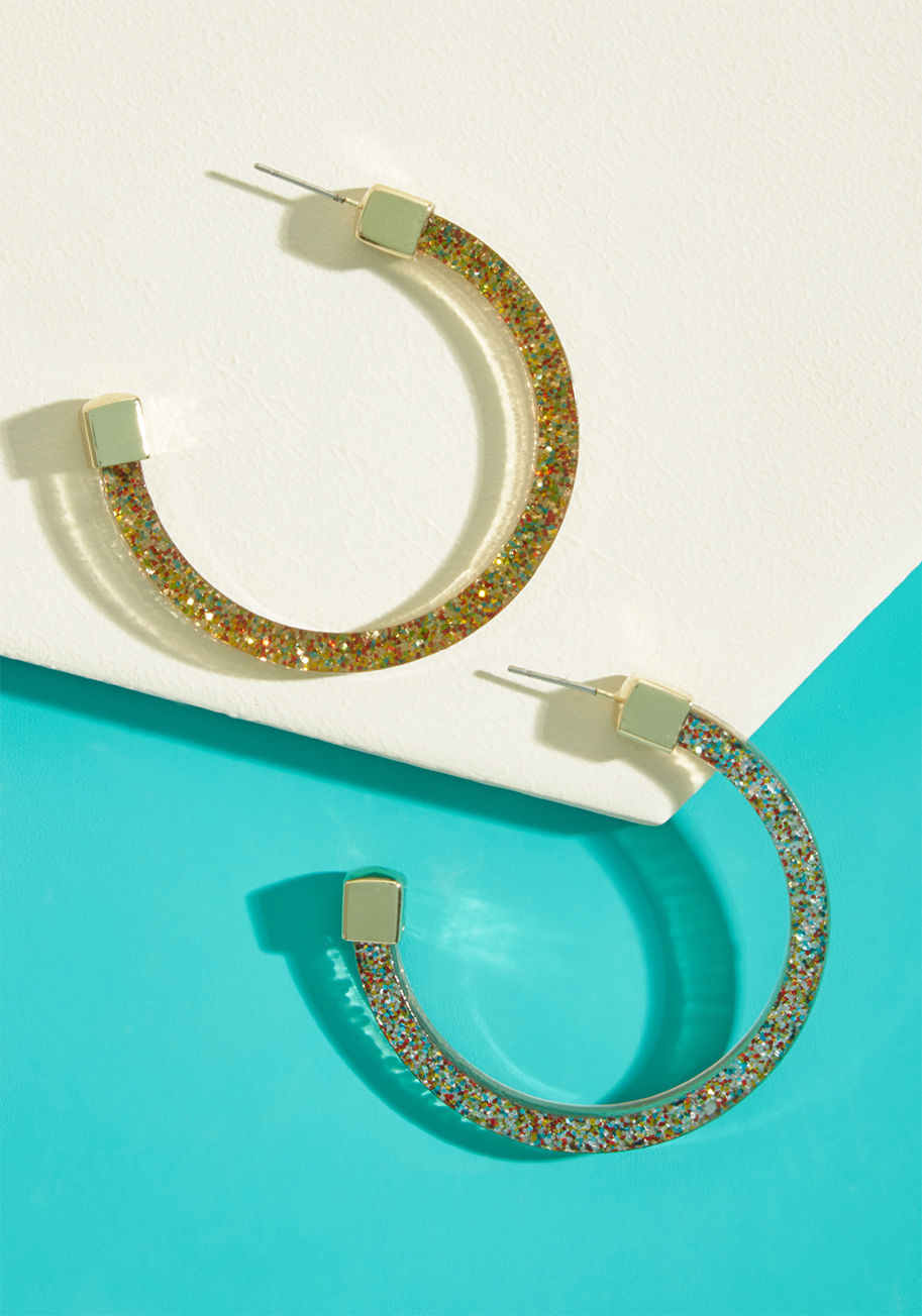 EA66968 - Take on the day with the genuine tenacity these hoop earrings inspire! Sparkling with glitter through their translucent frames, this gold-topped pair is a revved-up reminder that you can nail it on the daily.