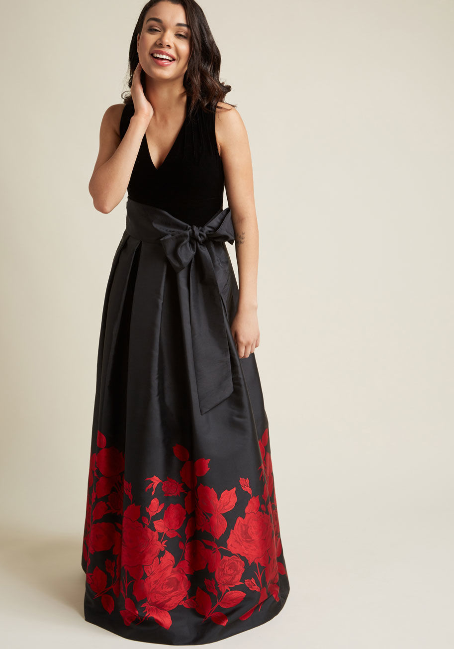 EJ7M6714 - Velvet on top, floral jacquard on bottom - this black gown from Eliza J masters textiles with truly elegant finesse! A V-neckline, dramatic sash, pleats, and secret pockets also contribute to the ultimate allure of this fine formalwear, guaranteeing a las