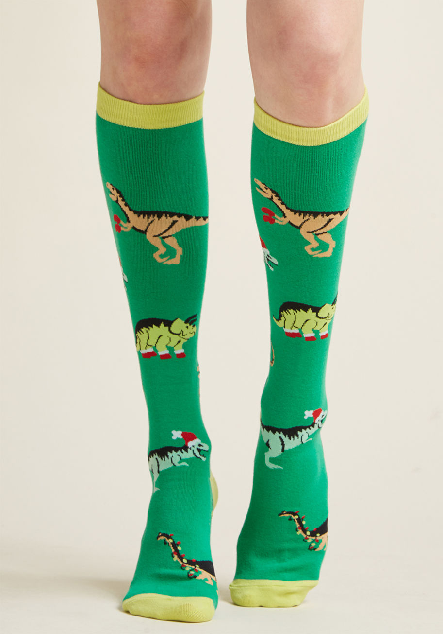 F0245 - These bright green knee socks will have you well on your way to a legendary holiday celebration! Rocking neon trim, dinos dressed up for the season, and a comfy knit construction, this pair is pretty much all you need to win at Christmas.