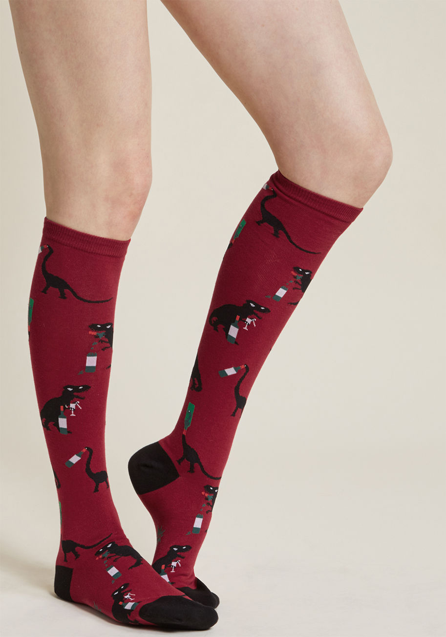 F0408 - If your preference for a good vintage extends past libation preference and into prehistoric matters, then these red socks are your perfect match! The black dinos atop these quirky knee highs are having a roaring time while imbibing a bottle or two, mirror