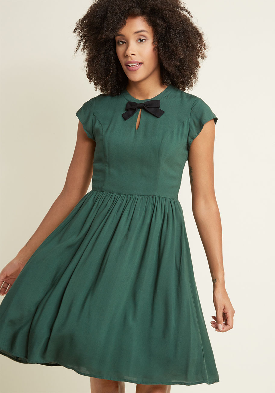 FA17MCD1394A - Retro frocks just don't get more darling than this dark green dress - a proud part of our ModCloth namesake label! Once you slip into this A-line's cap sleeves - positioned on either side of its black bow and adorable keyhole - its princess seams, and its