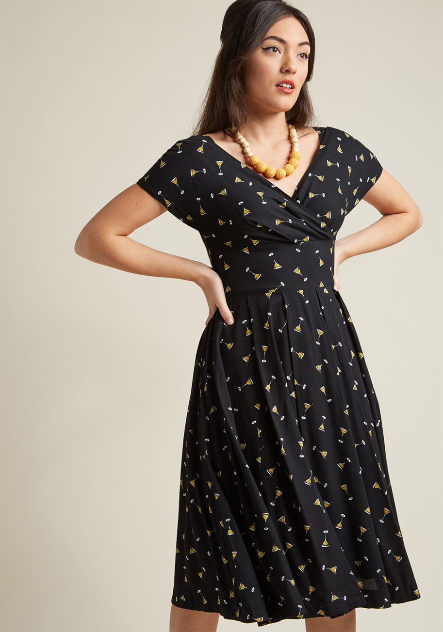 GBD-0189VR - Jazzing up the classic silhouette of this black midi dress from Emily and Fin is an adorable print of teeny martinis, but the fun doesn't end there! Cap sleeves, a surplice neckline, and crisp pleats also contribute to the timeless look of this pocketed n