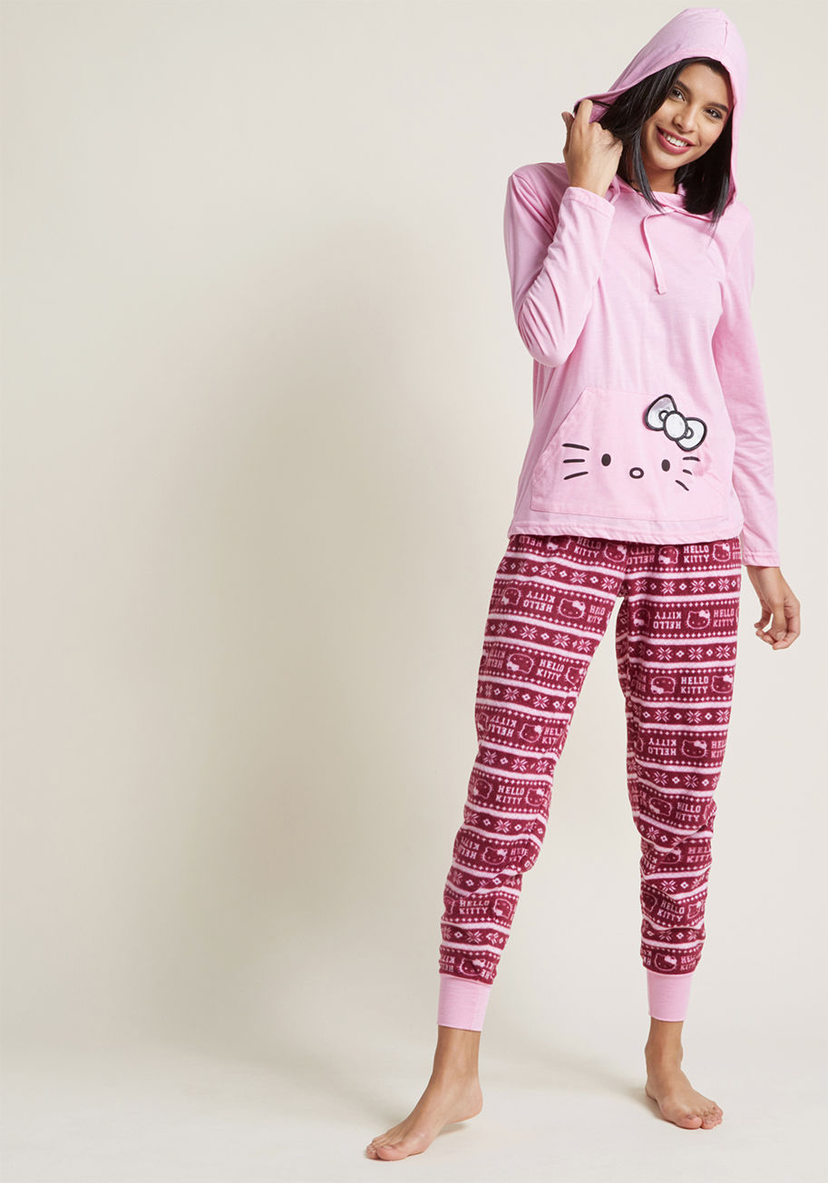 H82105 - You're your happiest when you're snuggled up with cartoons and these cute Hello Kitty pajamas! The bright pink hoodie's pouch pocket is screen printed with a silver version of that familiar face, while the fleece joggers flaunt an on-theme fair isle print