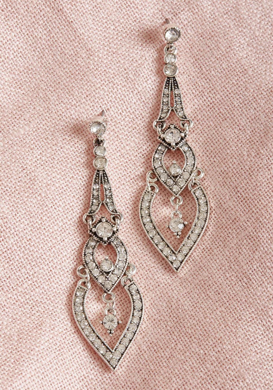 IMG-1862 - Embody the allure of Old Hollywood glamour by bedecking your lobes with these silver statement earrings! Sure to shine at your most special engagements, this pair melds soft, architectural shapes with gleaming rhinestones from post to point. Don't let the