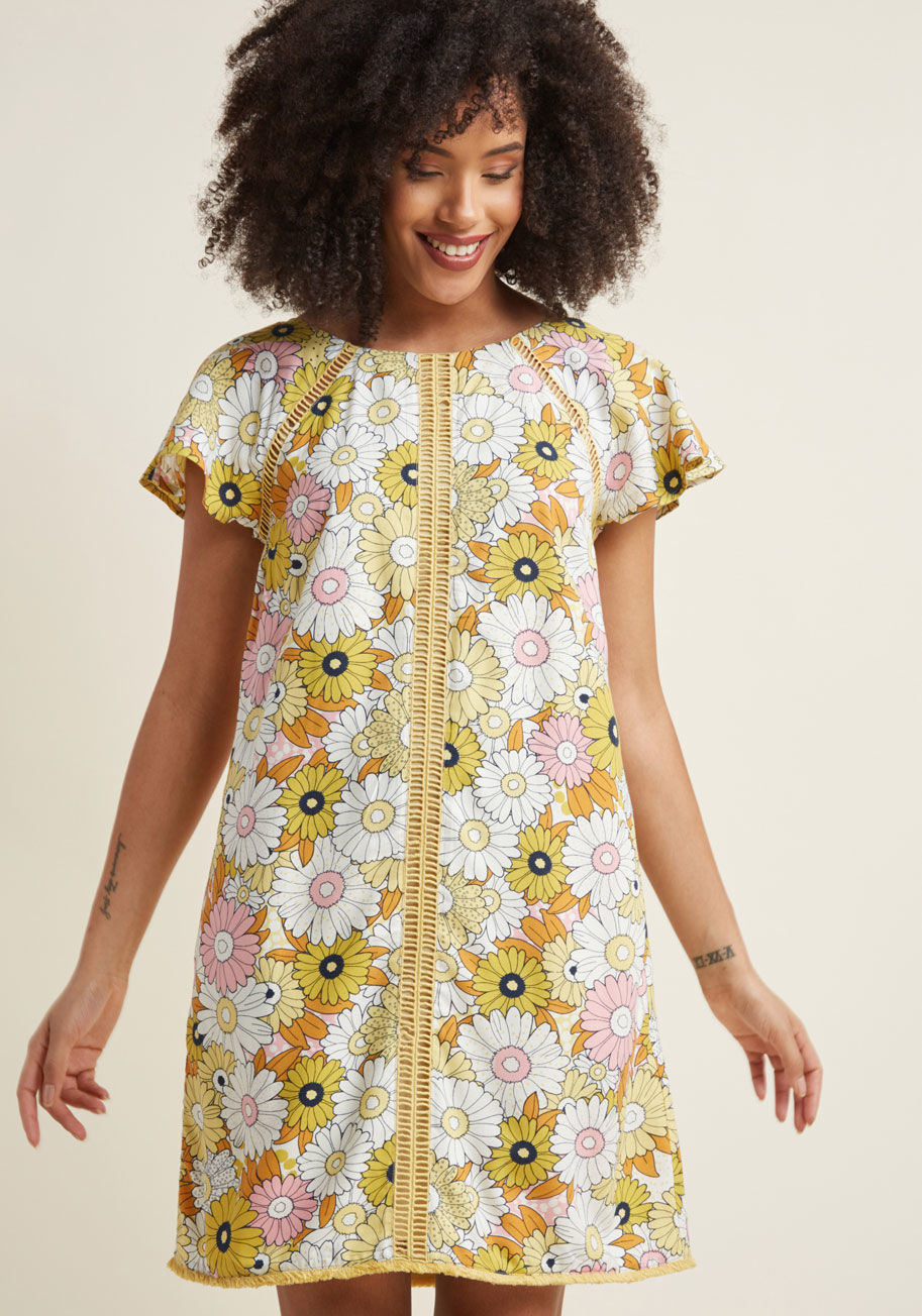 MCD1205A - Opening your wardrobe to rediscover this flirty shift dress each day is nothing short of a pure delight! A pale yellow hue highlights the retro florals that pattern this flowy dress, while hidden pockets, fluttery sleeves, and ladder piping at the shoulde