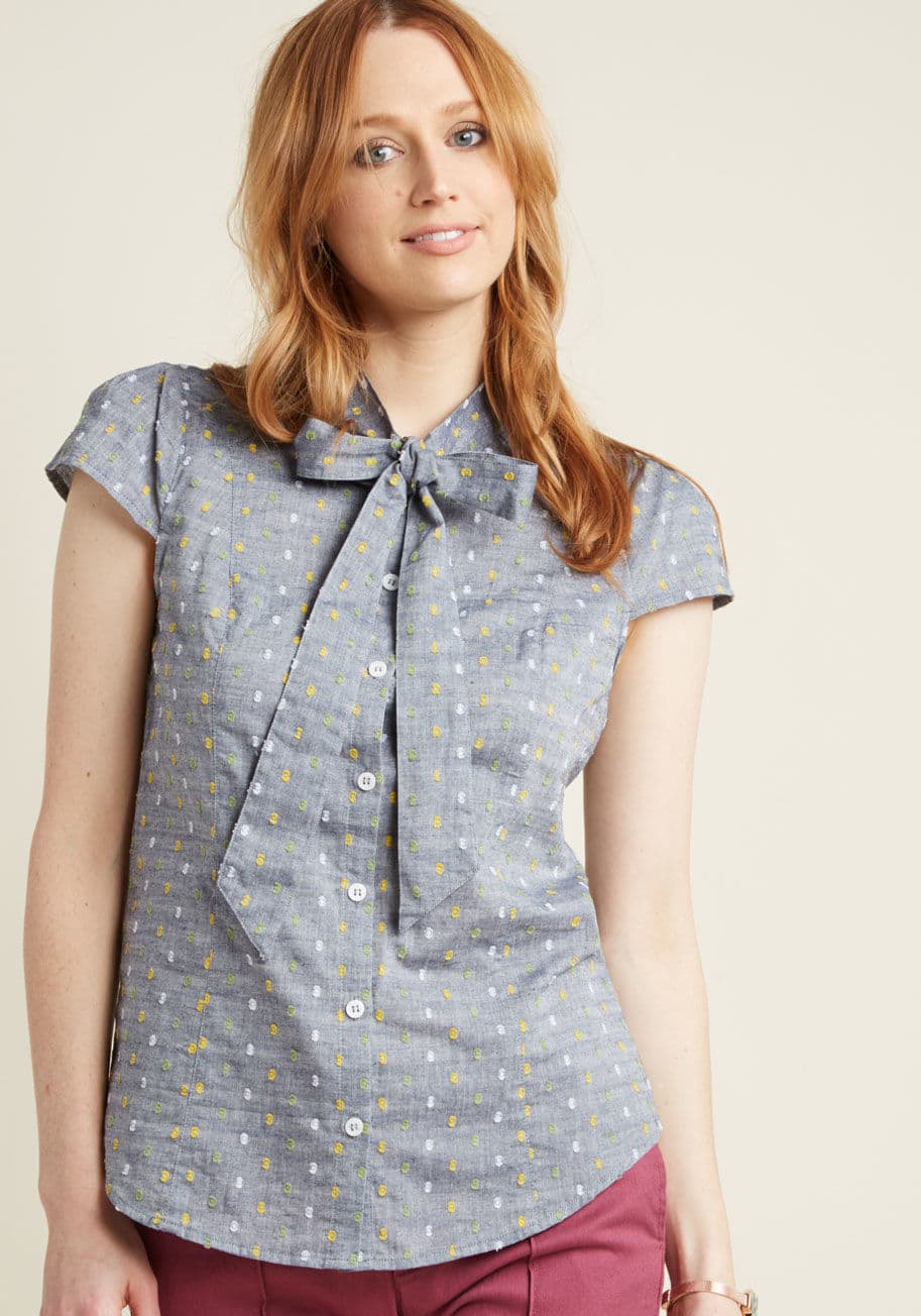 MCT1365 - Wear this chambray blouse like a badge earned for your expert take on polished style! A lovely number from our ModCloth namesake label, this grey top awards your outfit with a tied neckline, sleek buttons, and colorful collection of green, yellow, and whi