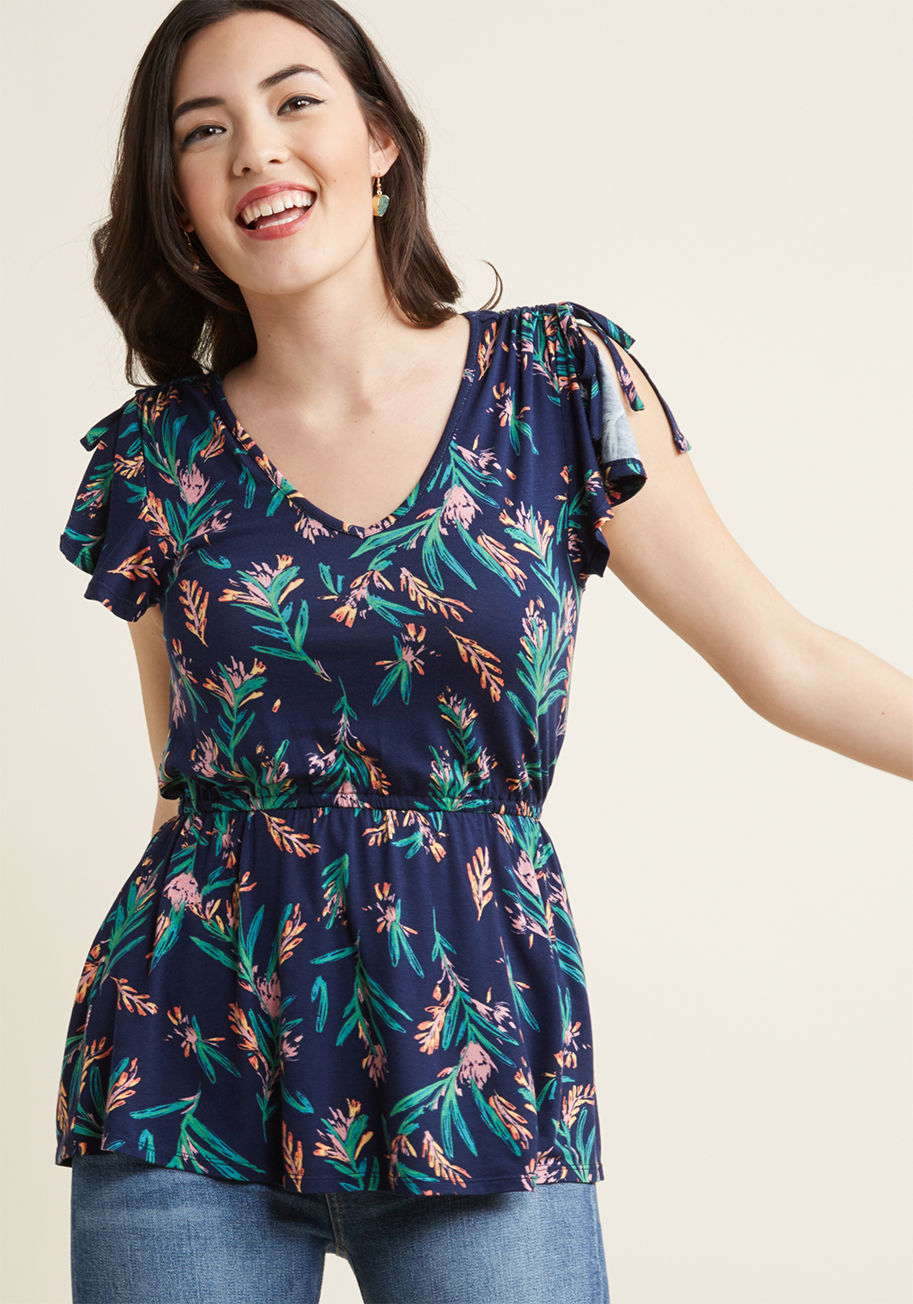 MCT1601A - Experience the thrill of a flaunting a fresh aesthetic with this floral navy top - even after its debut wear has long passed! With sleek ties ruching each shoulder, vents adding moment to its cap sleeves, and a peplum detail finishing the look, this ModCl