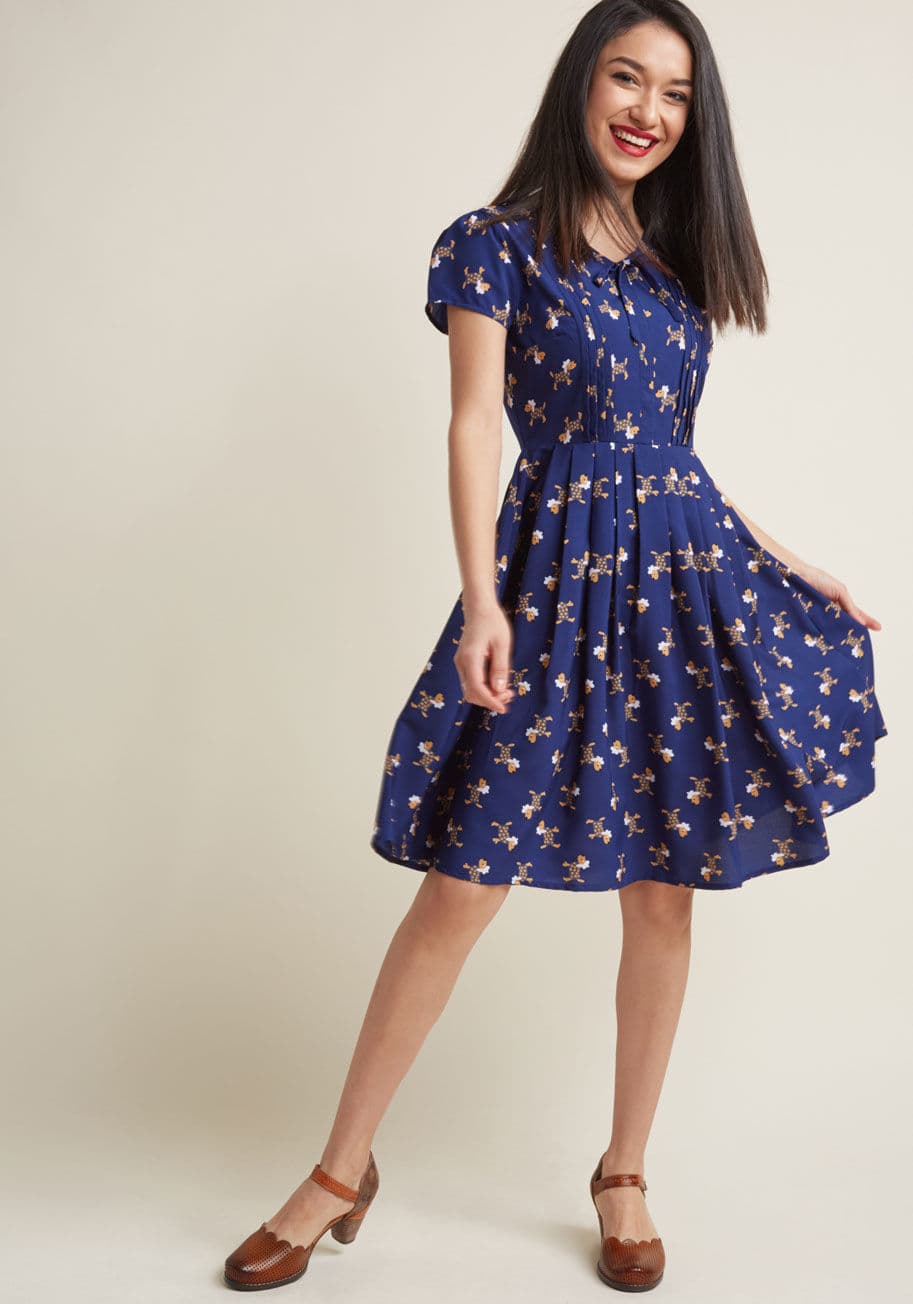 MDD1134A - Those seeking unique details to freshen up their wardrobe will go wild over this navy A-line dress! Though its bow-topped V-neckline and pleated skirt can be considered classic accents, its pintucked bodice and quirky Parisian pup pattern take it to a new