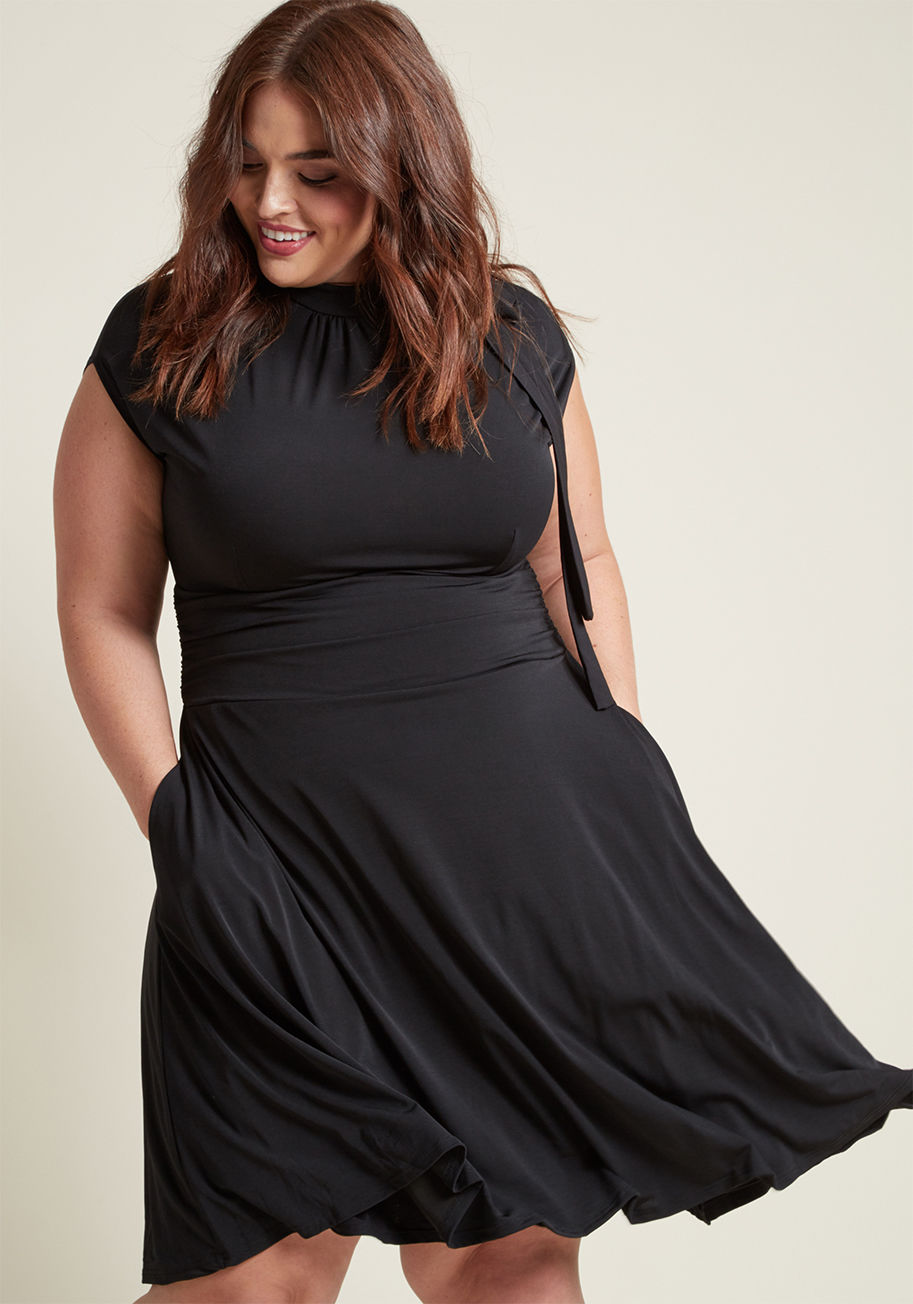 MDD1155 - Jump into this black dress and meet your darling on the dance floor! The bow-topped neckline of this look bounces with your every tango step, while the ruched details hug your waist as you flash your footwork. With a retro-infused shape, this pretty piece