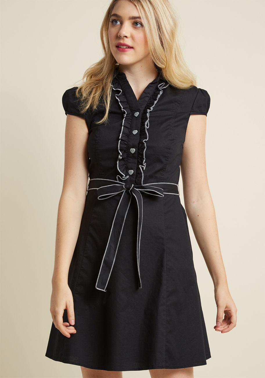 MDD1182 - This delightful black shirtdress grew up dreaming about one day becoming a fashion icon. Today, it's on its way with dapper ruffles, heart-shaped buttons and precise grey trim to round out its repertoire. We'd call that a success!