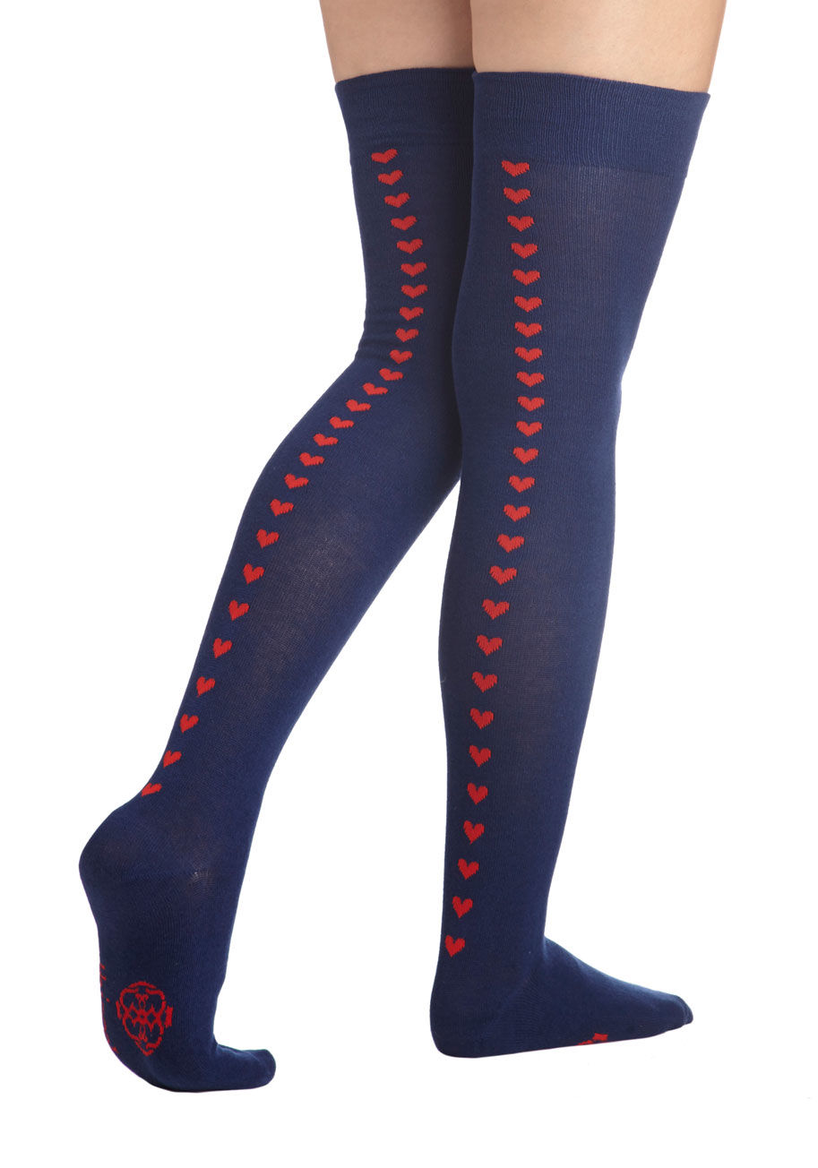 OTK1130-77 - These over-the-knee socks by Tabbisocks are sure to become a significant part of your life! A soft navy knit plays host to a trail of red hearts that travel from your ankle to the back of your thigh, peeking out beneath your plaid A-line skirt and Oxford 