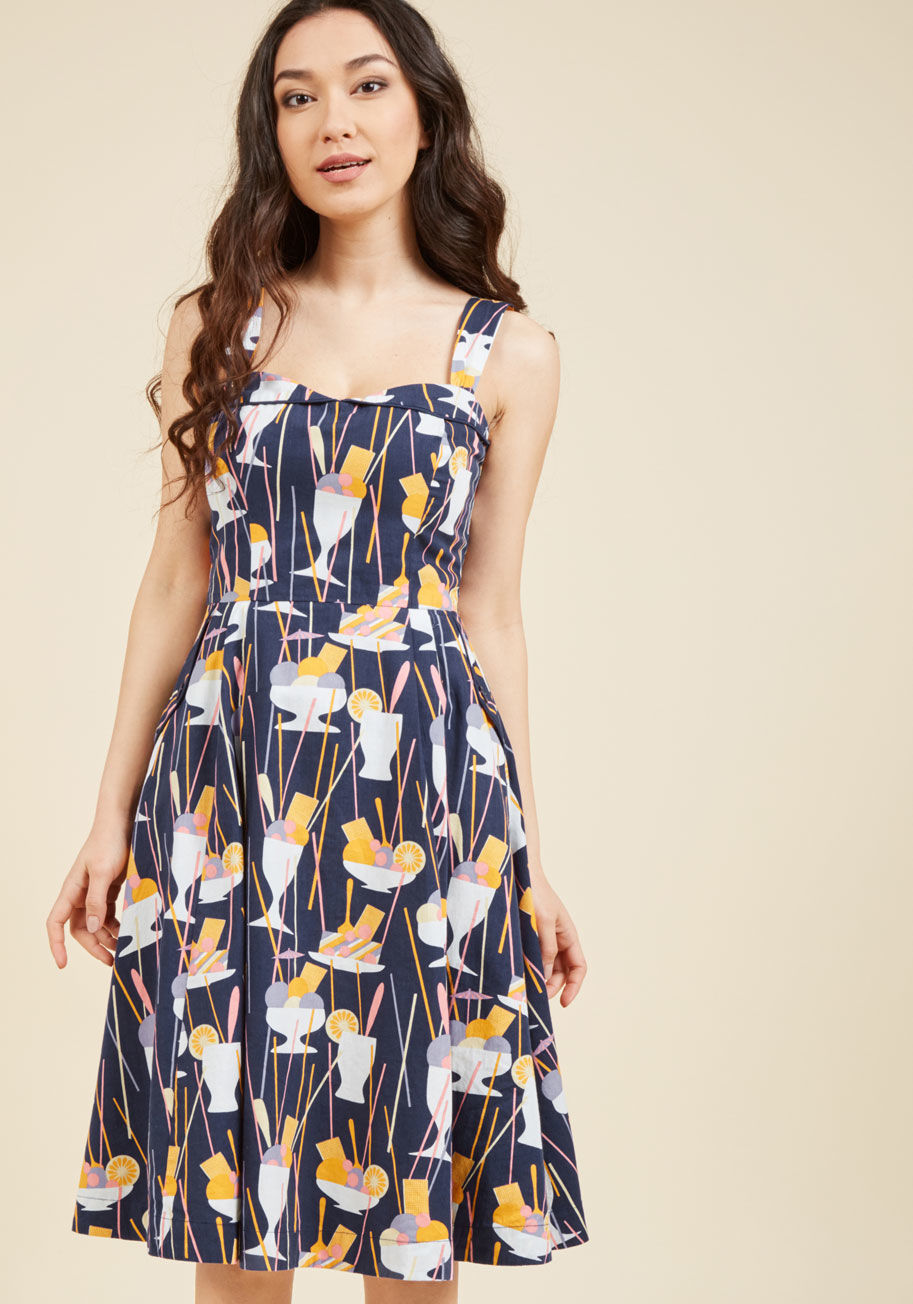 PID-0155CP - A vintage-inspired ensemble shouldn't take eons to create! This navy blue dress by hard-to-find British brand Emily and Fin completely agrees, which is why its foldover collar, deep pockets, and delectably dandy print of orange, lilac, and vanilla dessert