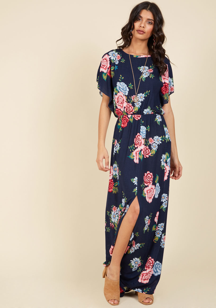 RR986 - As ethereal as the cherry blossoms blooming around you, this navy blue maxi dress embodies your grace and grandeur. Made of an airy, woven fabric, and finessed with red, pink, and sky blue flowers, dramatic flutter sleeves, and an off-centered vent on its