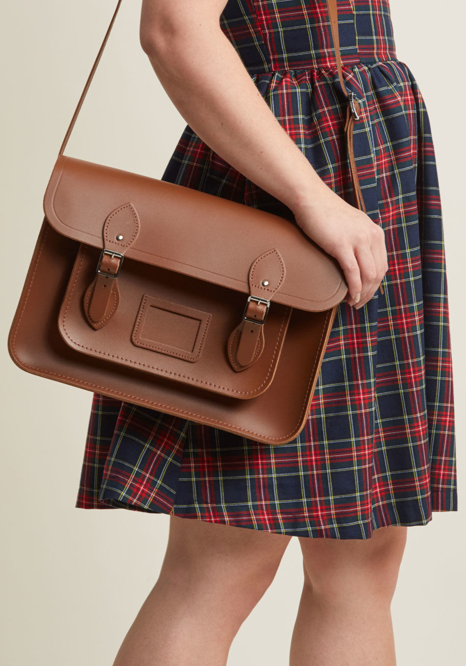 SAT141009MBN10101 - This brown bag, undeniably designed by The Cambridge Satchel Company, is absolutely saturated with classic style! A sturdy-yet-smooth, genuine leather composition hosts the handy magnetic buckles, luggage tag frame, dimensional front pocket, and essential