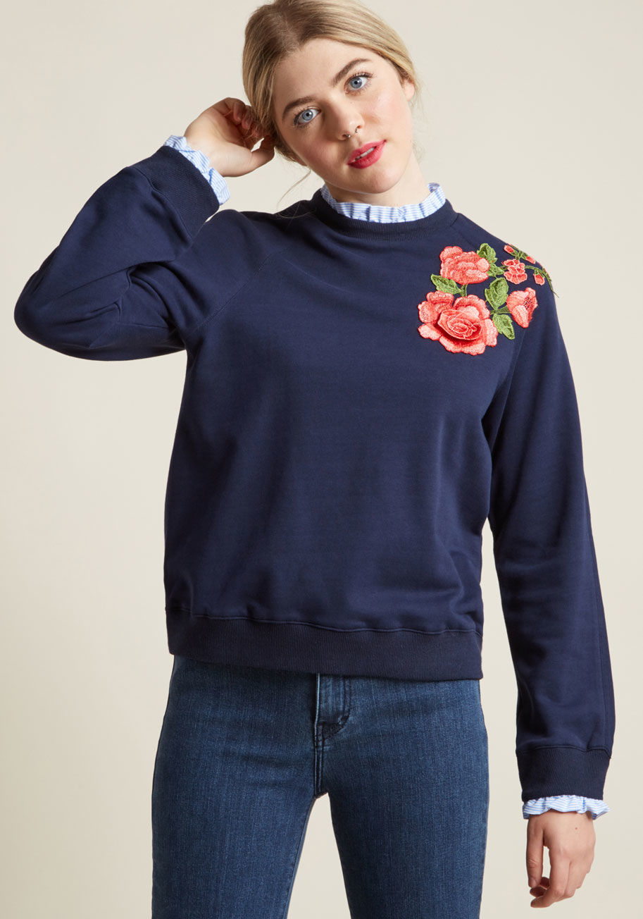 T94433 - It's no mystery that this navy sweatshirt is your preferred travel buddy for a bookstore trip. The blue-and-white striped ruffles at the collar and cuffs of this pullover are pure style poetry, while the pink and green embroidery and floral applique add a