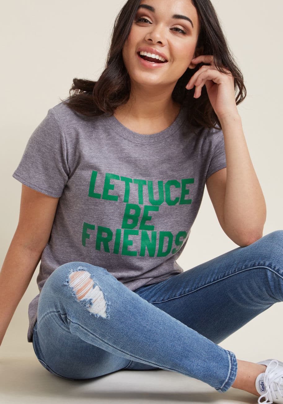 W3018-54 - Once this heather grey tee brings pals together, together you will 'romaine.' Why's that? With its crew neck, short sleeves, and green block letter graphic, you better 'bay leaf' that this roomy tee is just the beginning of a pun-filled friendship that ca