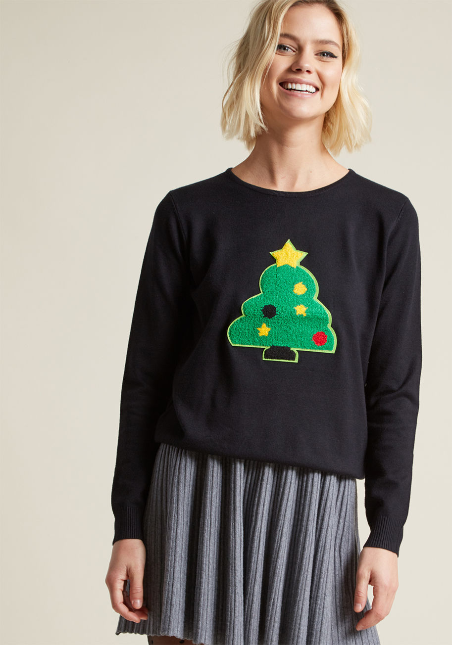 WI17NOI23 - Even your most casual moments can be full of holiday cheer, as long as this black knit top from Compania Fantastica is around! What was once a simple sweater has now become a festive essential, thanks to a chenille Christmas tree patch, ornaments and all.